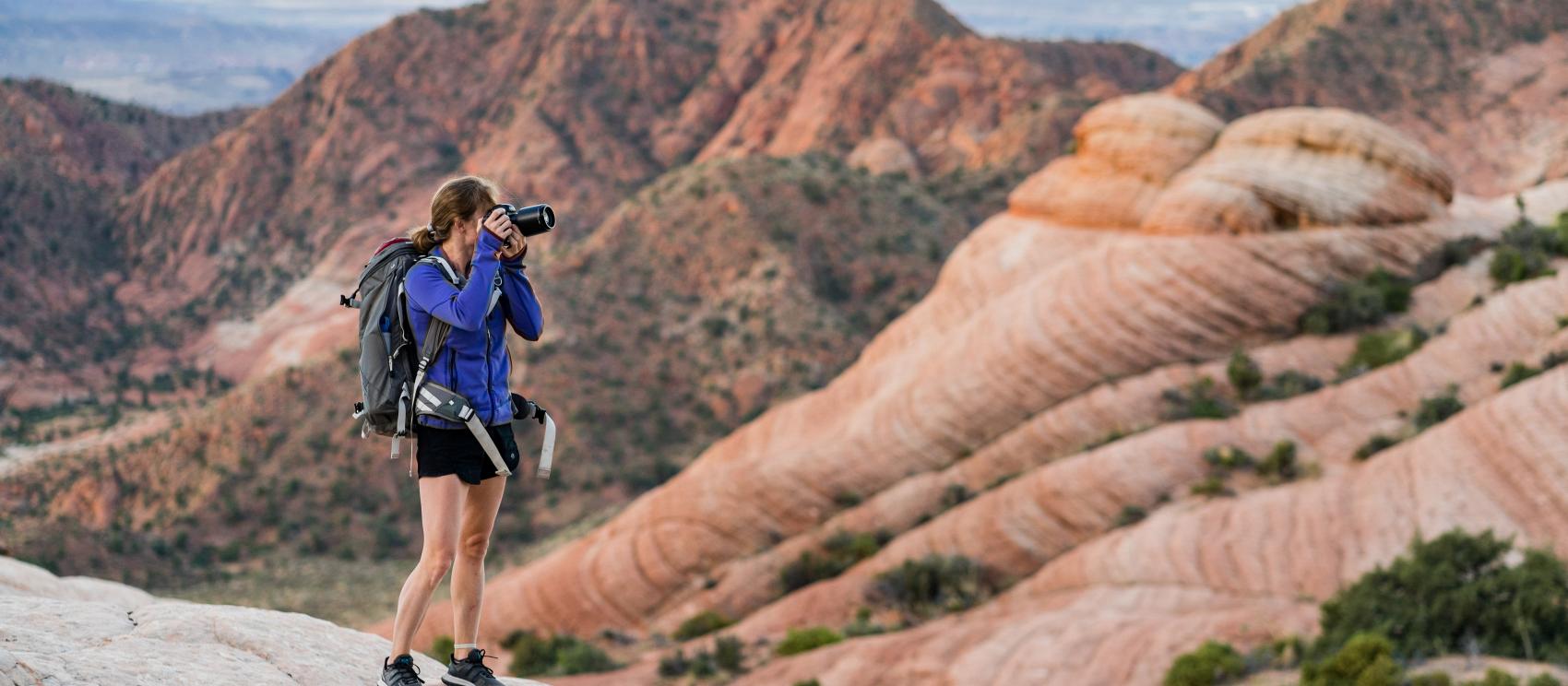 A hiker photographing the multi-colored Yant Flat formations near St. George A hiker photographing the multi-colored Yant Flat formations near St. George