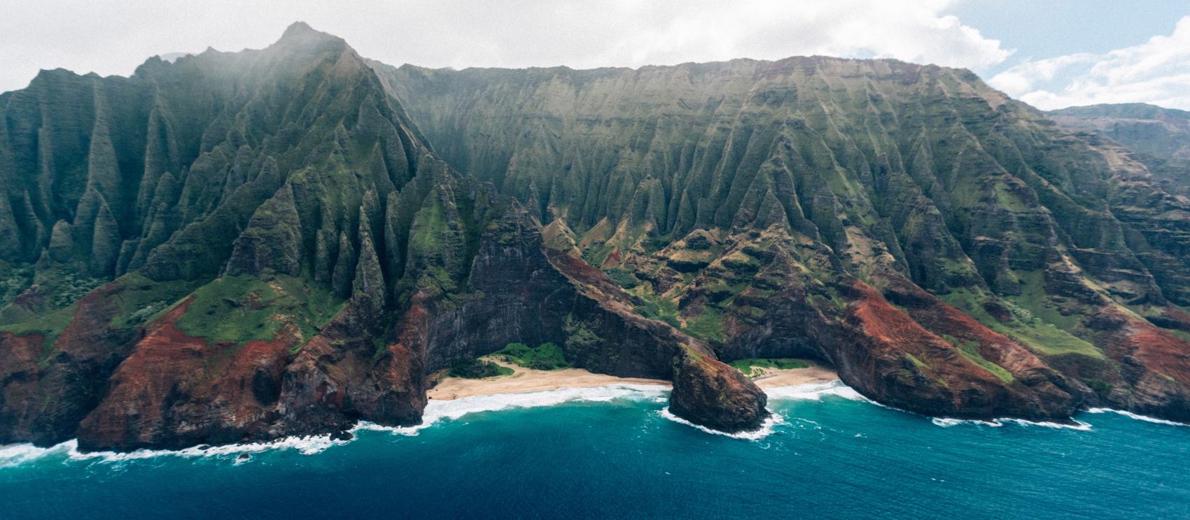 Towering sea cliffs meet the Pacific Ocean at Nāpali Coast State Wilderness Park on Kauaʻi Towering sea cliffs meet the Pacific Ocean at Nāpali Coast State Wilderness Park on Kauaʻi